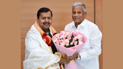V. Somanna presenting a bouquet of pink roses to a man honoured with a shawl and garland