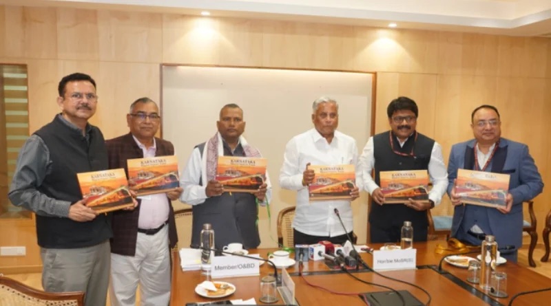 V. Somanna standing with railway officials, each holding a copy of a book on the Karnataka Bharat Gaurav train, at a conference table